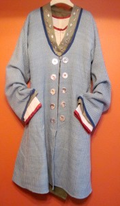 Full length view of the outer Kaftan layer. The fabric was woven from natural and indigo-dyed worsted wool in an original draft inspired by an extant example. It is edged with fine dark blue linen. All the seams are turned under and finished. The Kaftan pattern is based on an 8th century Alanic find at Moscevaya Balka.